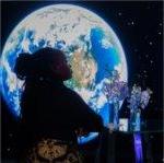 A visitor to GVSU's "The Blue Dot Experience," event is silhouetted against an image of the Earth.